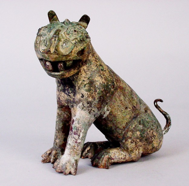 A ceramic sculpture of a dog sitting on the ground.