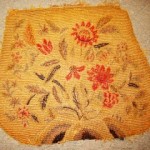 A yellow rug with flowers and leaves on it.