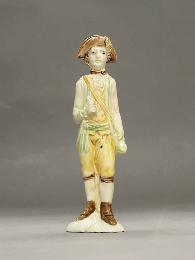 A ceramic statue of a boy in yellow pants and shirt.
