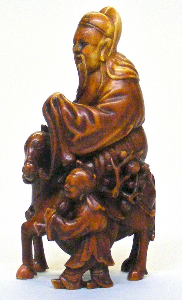 A wooden statue of a man sitting on top of a tree.