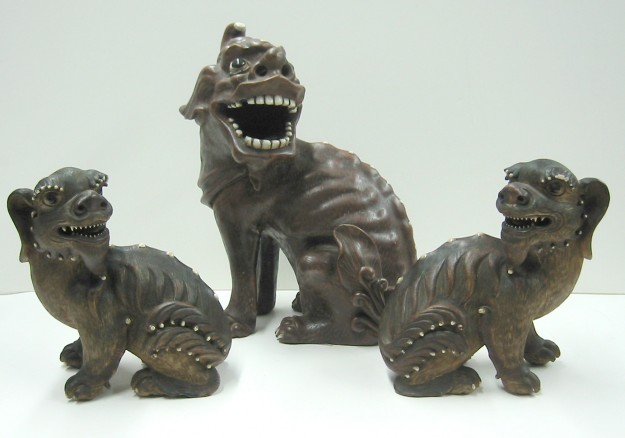 A group of three bronze statues of cats.