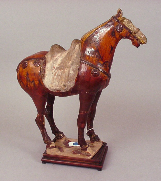 A wooden horse with saddle on top of it.