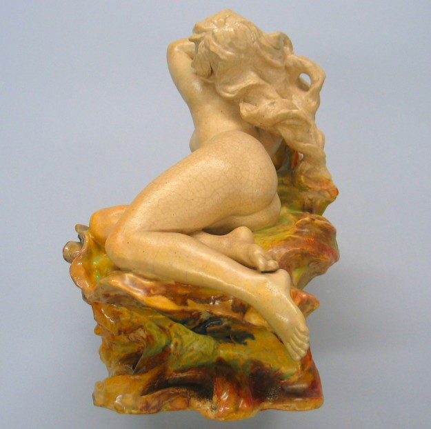 A statue of a woman sitting on top of a rock.