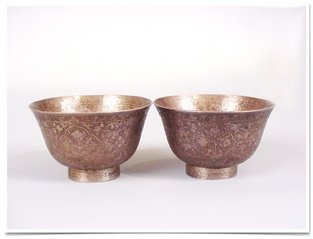 A pair of bowls with gold colored designs on them.