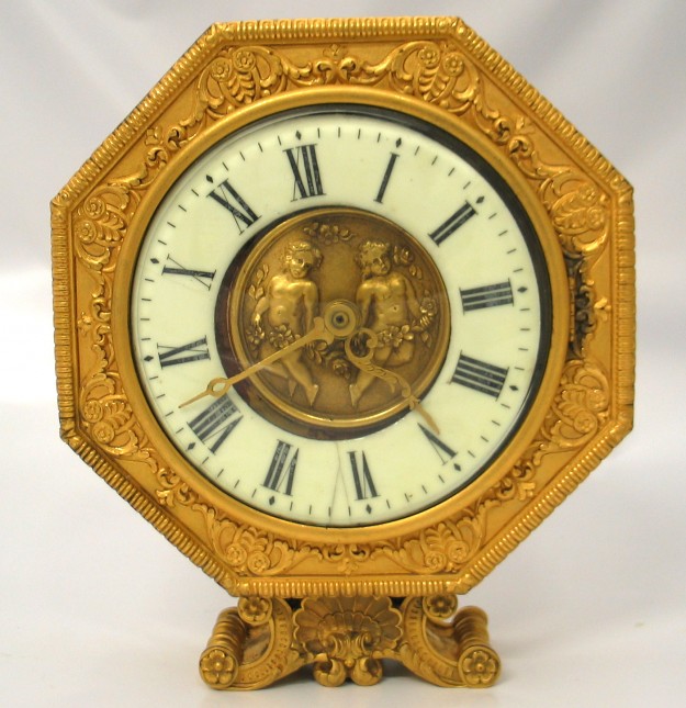 A gold clock with roman numerals and a roman numeral face.