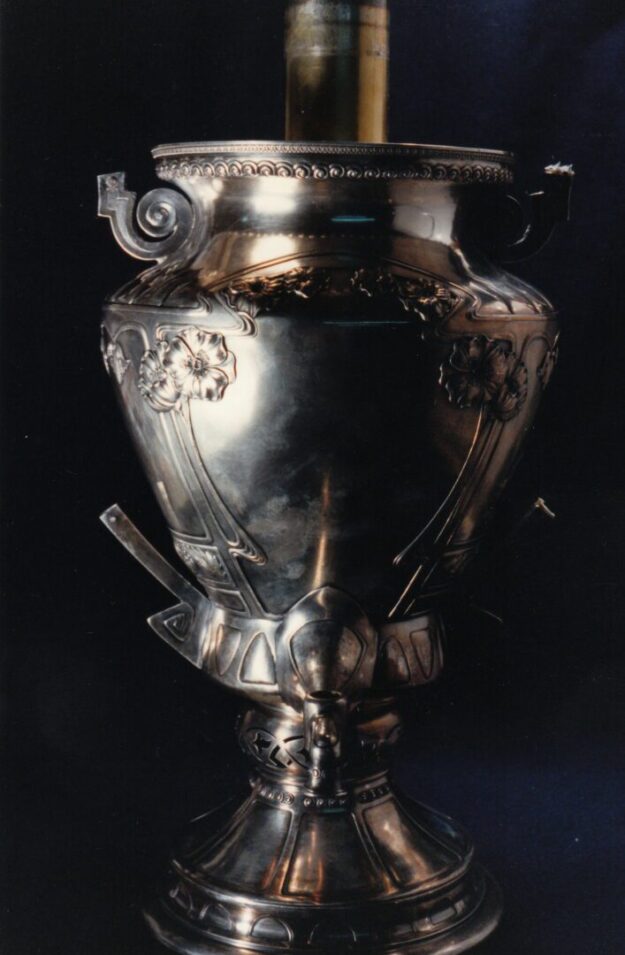 A silver vase with ornate designs on it.