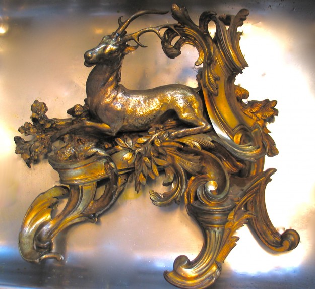 A gold colored sculpture of a deer on top of a metal surface.
