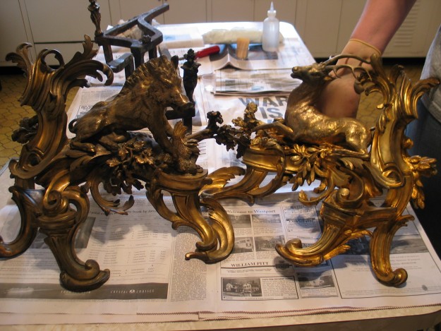 A table with two gold plated sculptures on it