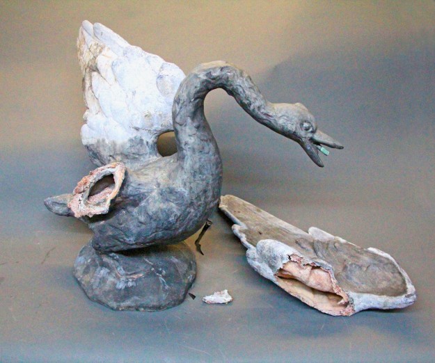 A broken swan statue sitting on top of a table.