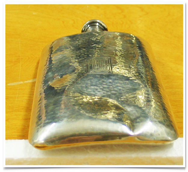 A silver flask sitting on top of a wooden table.