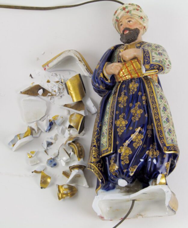 A broken figurine of a man in blue and gold.