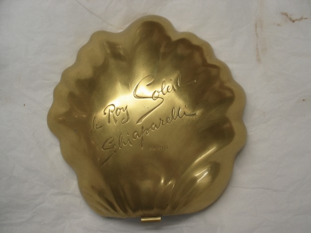 A gold shell shaped compact with the words " big sister, little sister ".