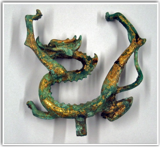 A green and gold dragon sculpture on top of a white wall.