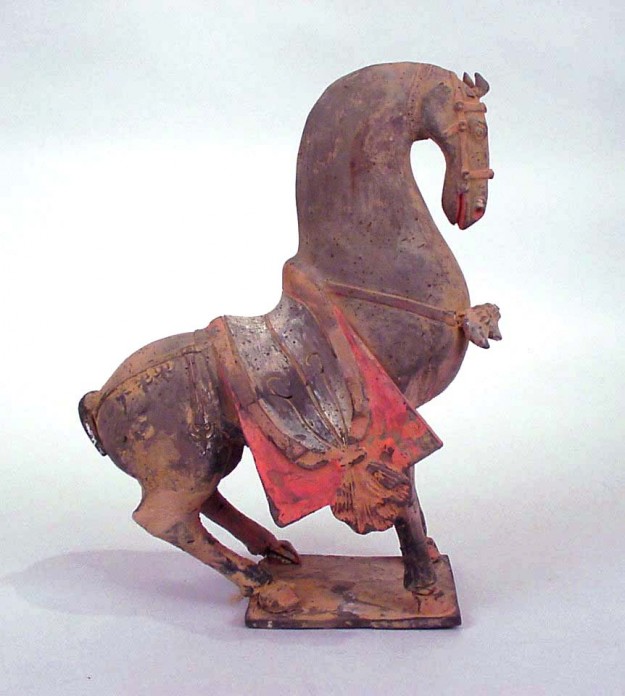 A horse statue with red saddle on it's back.