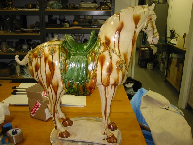 A ceramic horse is sitting on the table.