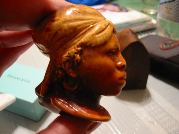 A person holding a wooden head with a brown hair style.