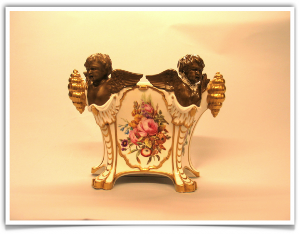 A white vase with gold trim and two cherubs.